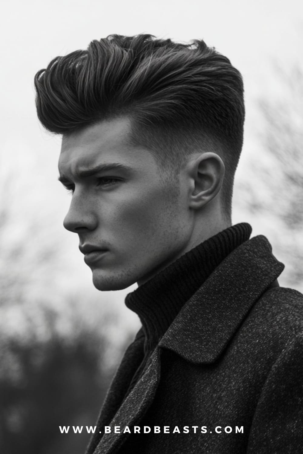 Black and white image of a man sporting a modern pompadour, one of the popular men's pomade hairstyles for 2024. His hair is styled with height and volume using pomade, with a clean fade on the sides.