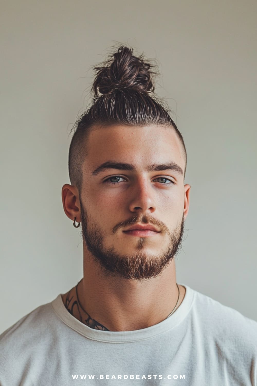 Man with a sharp top knot hairstyle, featuring shaved sides and a well-groomed beard, showcasing a bold and modern look. This trendy style is a popular choice for men's hairstyles for long hair, combining practicality with an edgy twist.