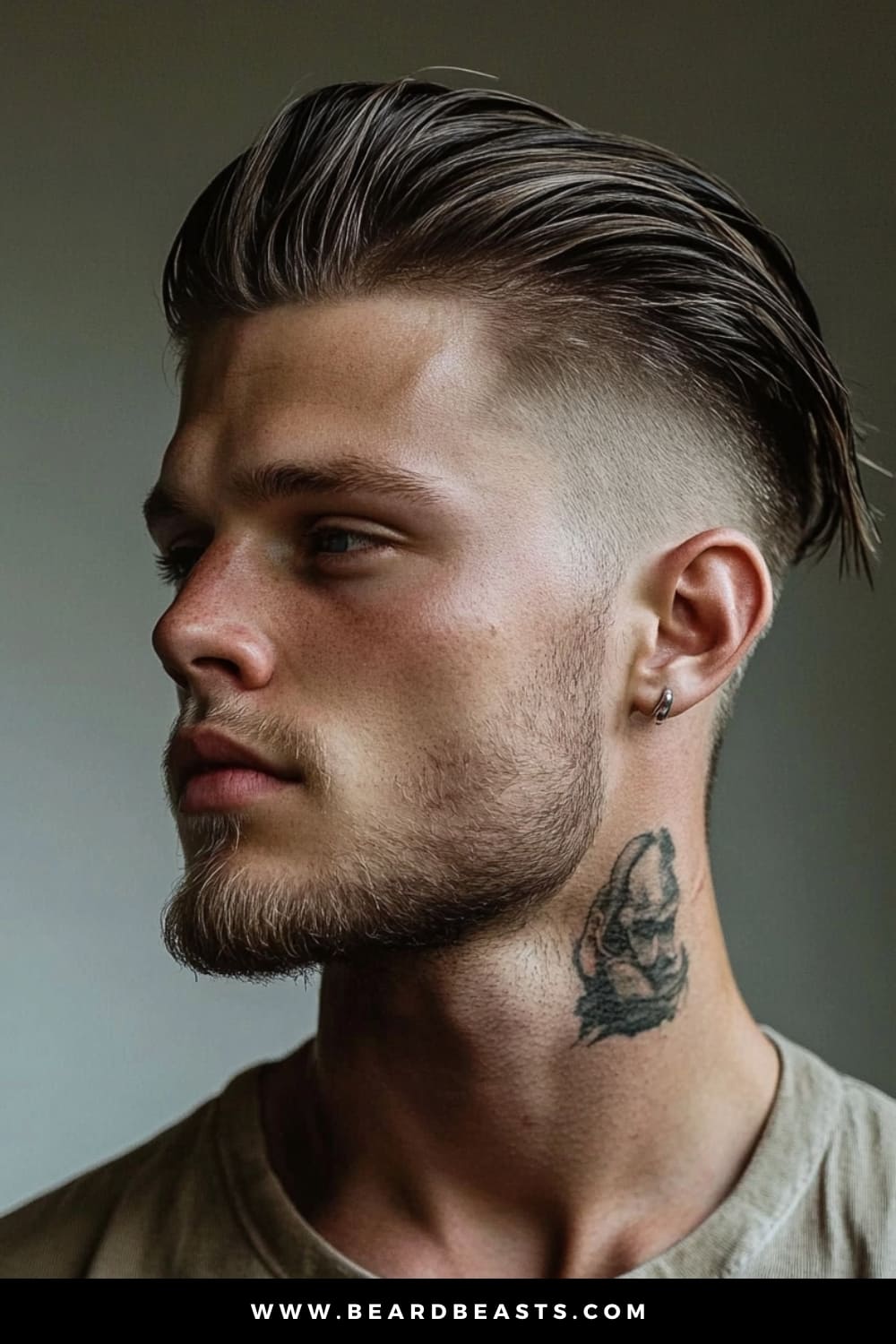 A young man confidently sporting an undercut with layers, one of the trendiest layered haircuts for men. The sides are sharply faded, creating a stark contrast with the longer, slicked-back layers on top, which add volume and texture to the hairstyle. His effortlessly styled top flows smoothly, giving the haircut a polished yet edgy vibe. Complemented by a subtle beard, a small hoop earring, and a bold neck tattoo, this look perfectly balances modern refinement with a rebellious edge.