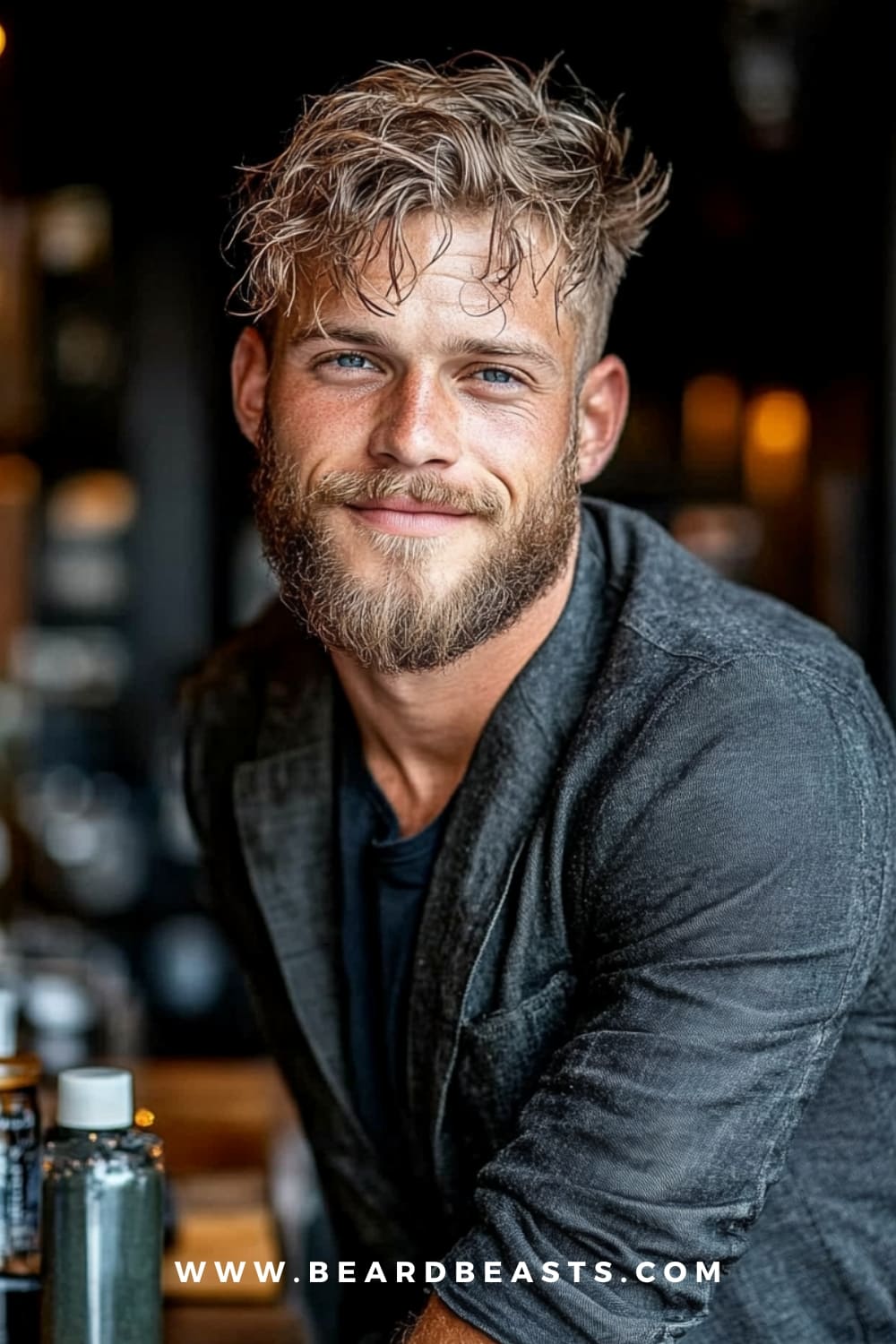 Man with messy, textured hair and a well-groomed beard, smiling in a casual outfit. Messy hair is a trendy and effortless option among low maintenance haircuts for men, offering a relaxed and stylish look with minimal grooming required.