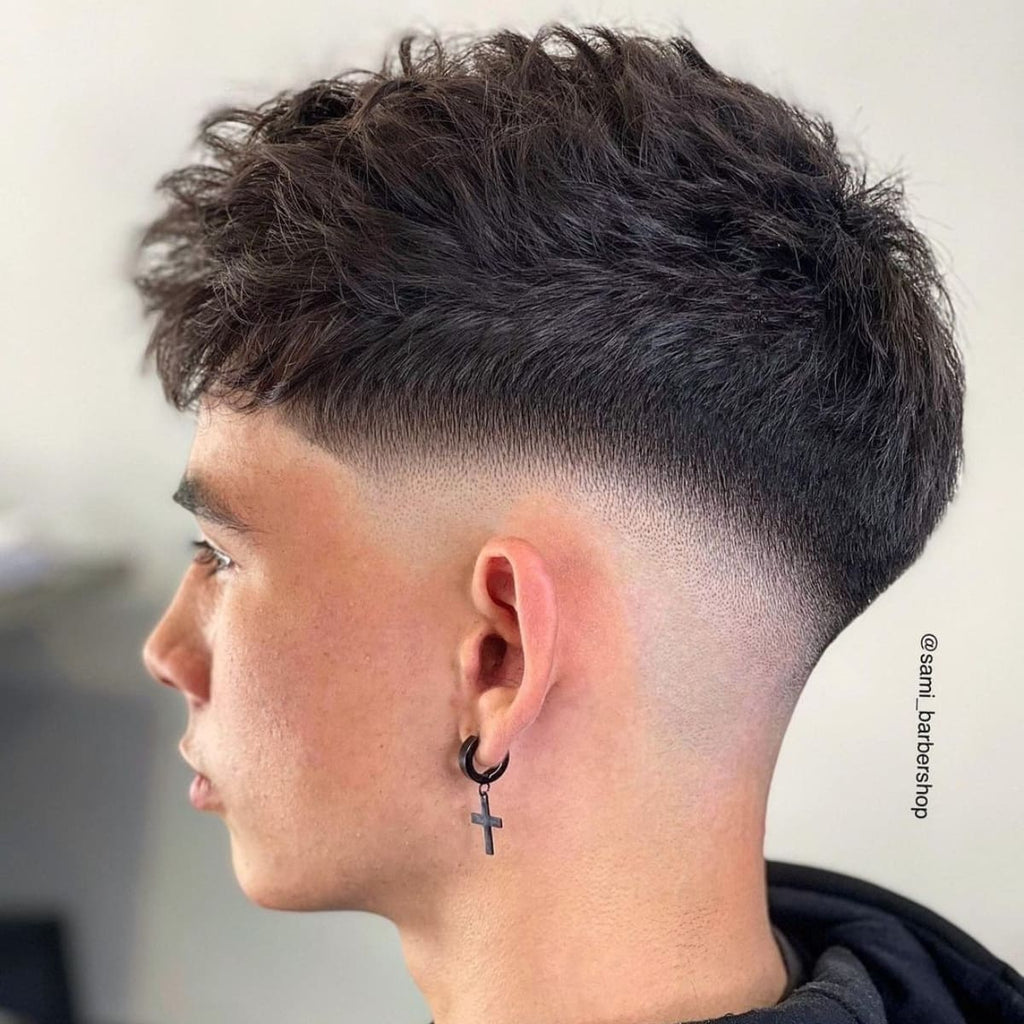 A side profile of a young man with textured, voluminous hair on top, tapering smoothly into a closely shaved fade on the sides and back.