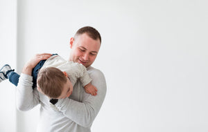 Father playfully lifting his young child, illustrating the joy of parenthood while highlighting the importance of self care for dads in balancing well-being and family bonding.