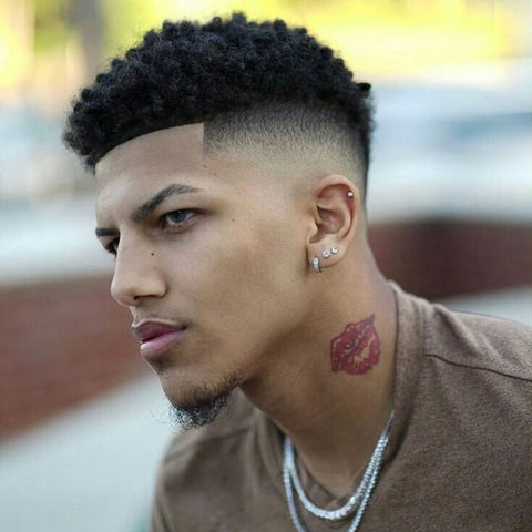 Man with a stylish Short Afro haircut, featuring tight, defined curls on top with a sharp fade on the sides. The clean, precise lines of the fade highlight the natural texture of the curls, creating a modern and fresh look that complements his facial features and accessories.