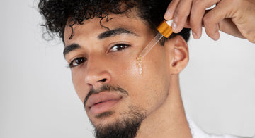 Man applying beard oil every day with a dropper as part of his daily beard care routine, highlighting the benefits of using beard oil for a soft and healthy beard.