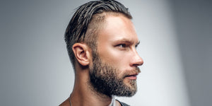 Side profile of a man with a slick back undercut hairstyle, featuring neatly slicked-back hair on top and short, faded sides. Perfect example of a modern slick back undercut for men.