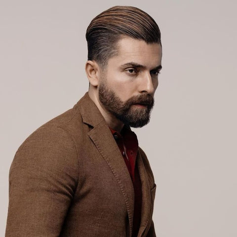 Portrait of a man with a slicked-back hairstyle, perfectly groomed and paired with a full beard. This classic hairstyles for men exudes sophistication and confidence, making it a timeless choice for both formal and casual settings. Ideal for those seeking a polished, professional look.