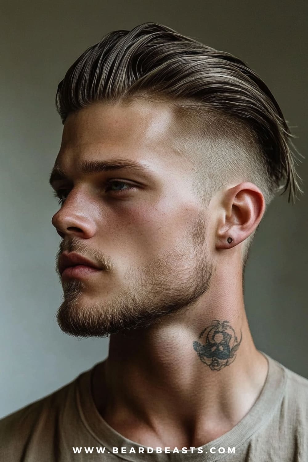 A young man with a strong, confident profile is showcasing a Slicked Back Undercut, a bold and modern choice among medium length hairstyles for men. His hair is slicked back smoothly, creating a sleek and polished look that contrasts sharply with the undercut sides, which are closely shaved for a striking, edgy appearance. The top section of his hair is left longer, adding volume and texture, while the back is neatly tapered. This hairstyle is ideal for men who want to combine a classic slicked-back style with a contemporary, daring twist. His well-groomed beard complements the hairstyle, enhancing his chiseled features.