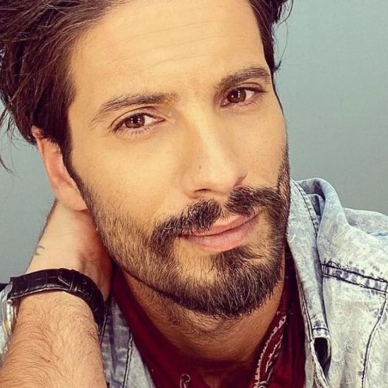 Handsome man with a stubble goatee, casual denim jacket, and a thoughtful expression