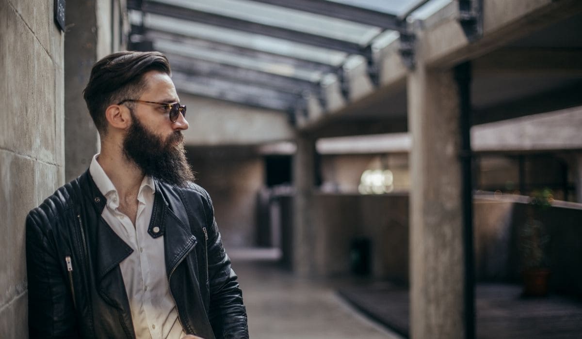 a bearded man leaning on the wall