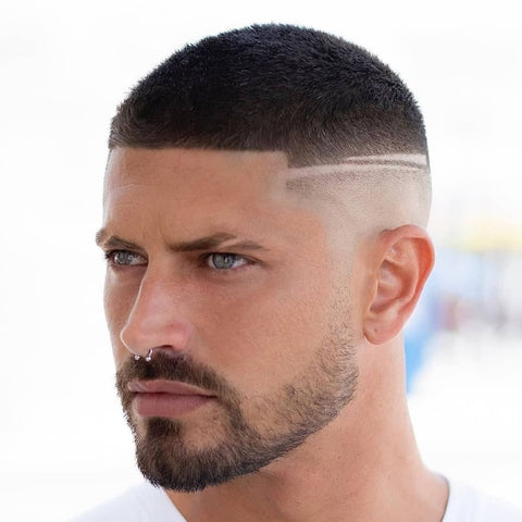 Close-up of a man with a modern crew cut hairstyle featuring a sharp fade and a geometric design shaved into the side. This classic men's hairstyle blends practicality with contemporary flair, making it an ideal choice for those seeking a clean, edgy look.