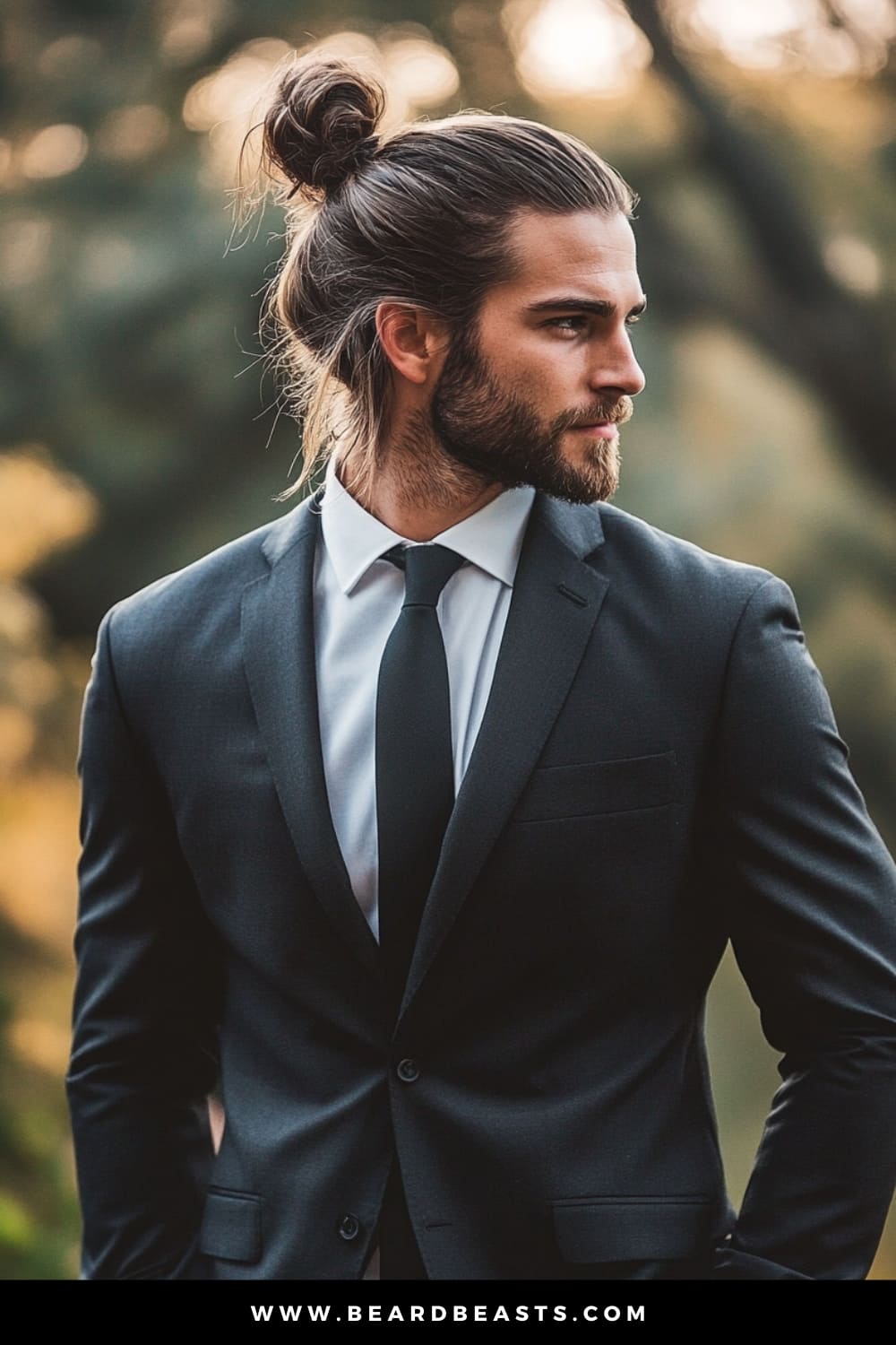 A groom with a stylish Man Bun hairstyle, exemplifying one of the most popular men's wedding hairstyles. His long hair is neatly tied back into a bun, creating a sophisticated yet relaxed look that perfectly complements his well-groomed beard. Dressed in a tailored black suit with a crisp white shirt and black tie, he exudes a modern and confident vibe, ideal for a rustic or outdoor wedding setting.