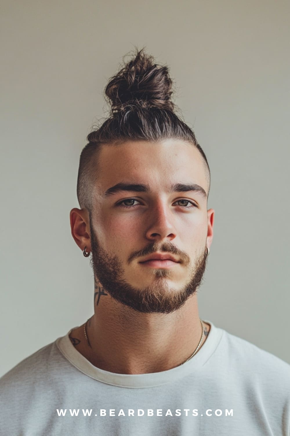 Man with a top knot and undercut hairstyle, paired with a well-groomed beard. The top knot with undercut is a bold and stylish choice among low maintenance haircuts for men, offering a modern look with minimal daily effort.