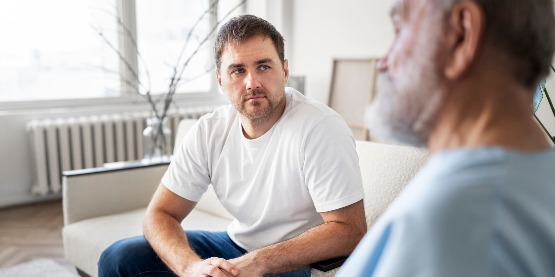 Two men engage in a thoughtful conversation, focusing on mental health as part of self-care for men. One man listens attentively, emphasizing the importance of open communication and emotional support in maintaining mental well-being.