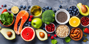 Assortment of nutritious foods like salmon, spinach, avocado, broccoli, blueberries, chia seeds, almonds, oats, and citrus fruits, highlighting what vitamins help beard growth.