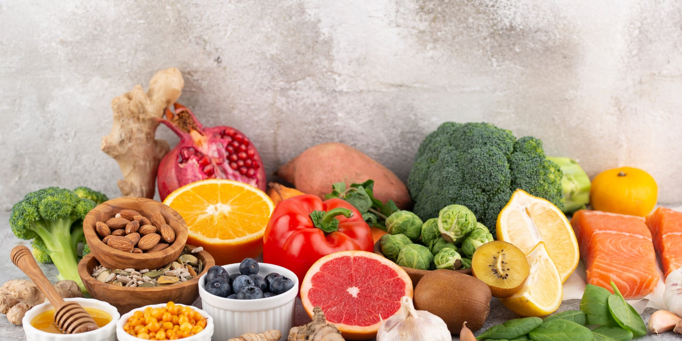 Colorful assortment of nutrient-rich foods including broccoli, almonds, citrus fruits, berries, pomegranate, sweet potatoes, and salmon, showcasing essential vitamins and minerals that promote beard growth and overall health.