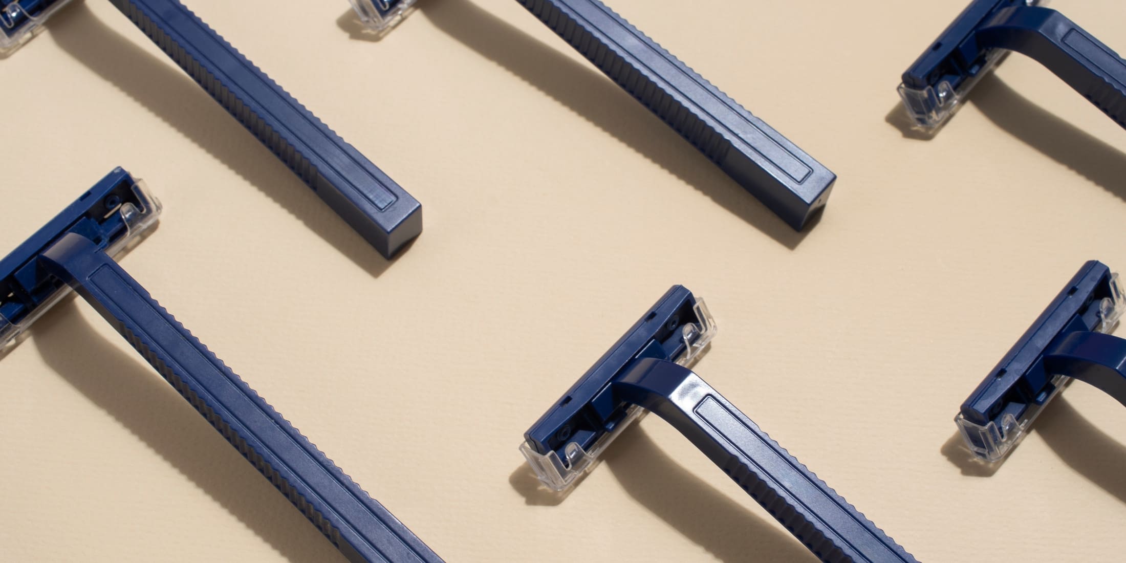 Multiple blue cartridge razors arranged neatly on a beige background, showcasing the design and structure of modern cartridge razors. Ideal for understanding the differences in the safety razor vs cartridge razor debate.