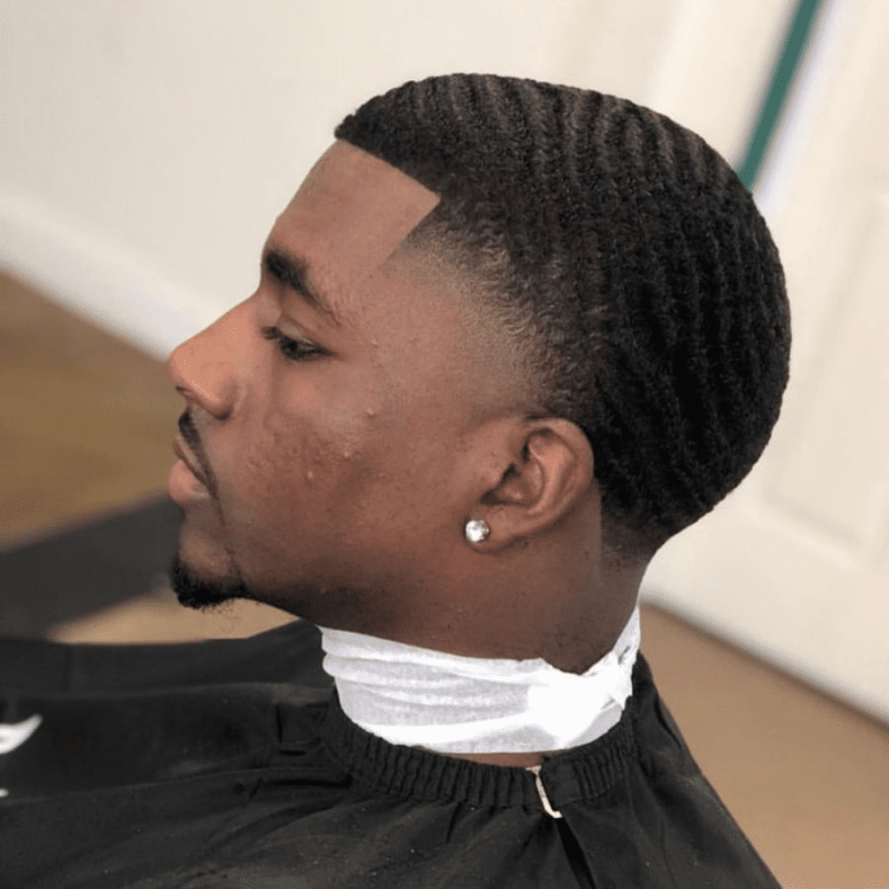 Side profile of a man with a 360 Waves haircut, featuring defined wave patterns on top and a clean fade on the sides and back. The hairstyle highlights the textured 360 waves, offering a stylish and modern look perfect for men seeking trendy haircuts