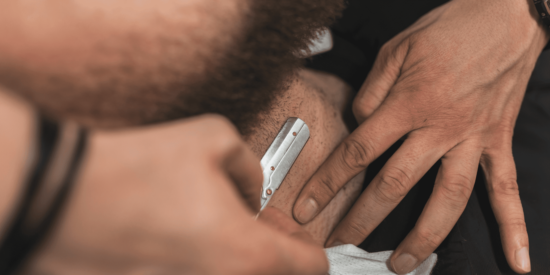 Close-up of a man shaving his neck with a straight razor, showcasing the precision and care involved in traditional shaving techniques. Learn how to shave with a straight razor for a precise, smooth shave.