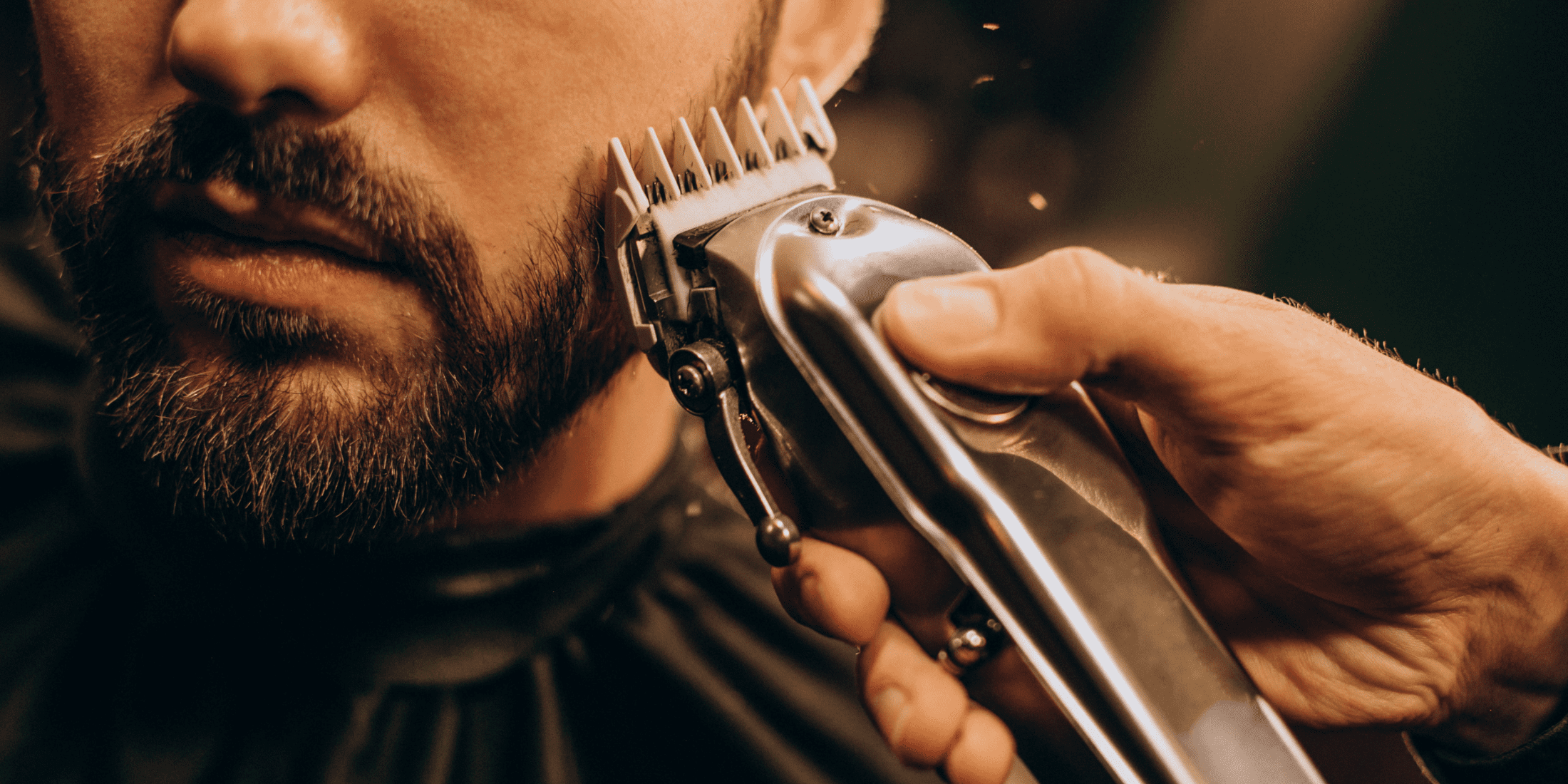 Close-up of a barber using clean clippers to trim a man's beard. Learn how to clean clipper blades for optimal grooming performance and hygiene.