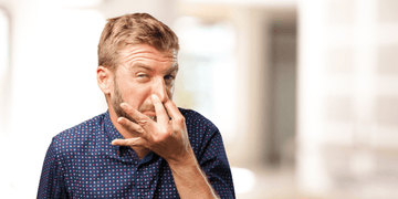 Man Holding Nose Due to Bad Beard Odor - Learn How to Prevent and Eliminate Beard Smells with Our Expert Tips