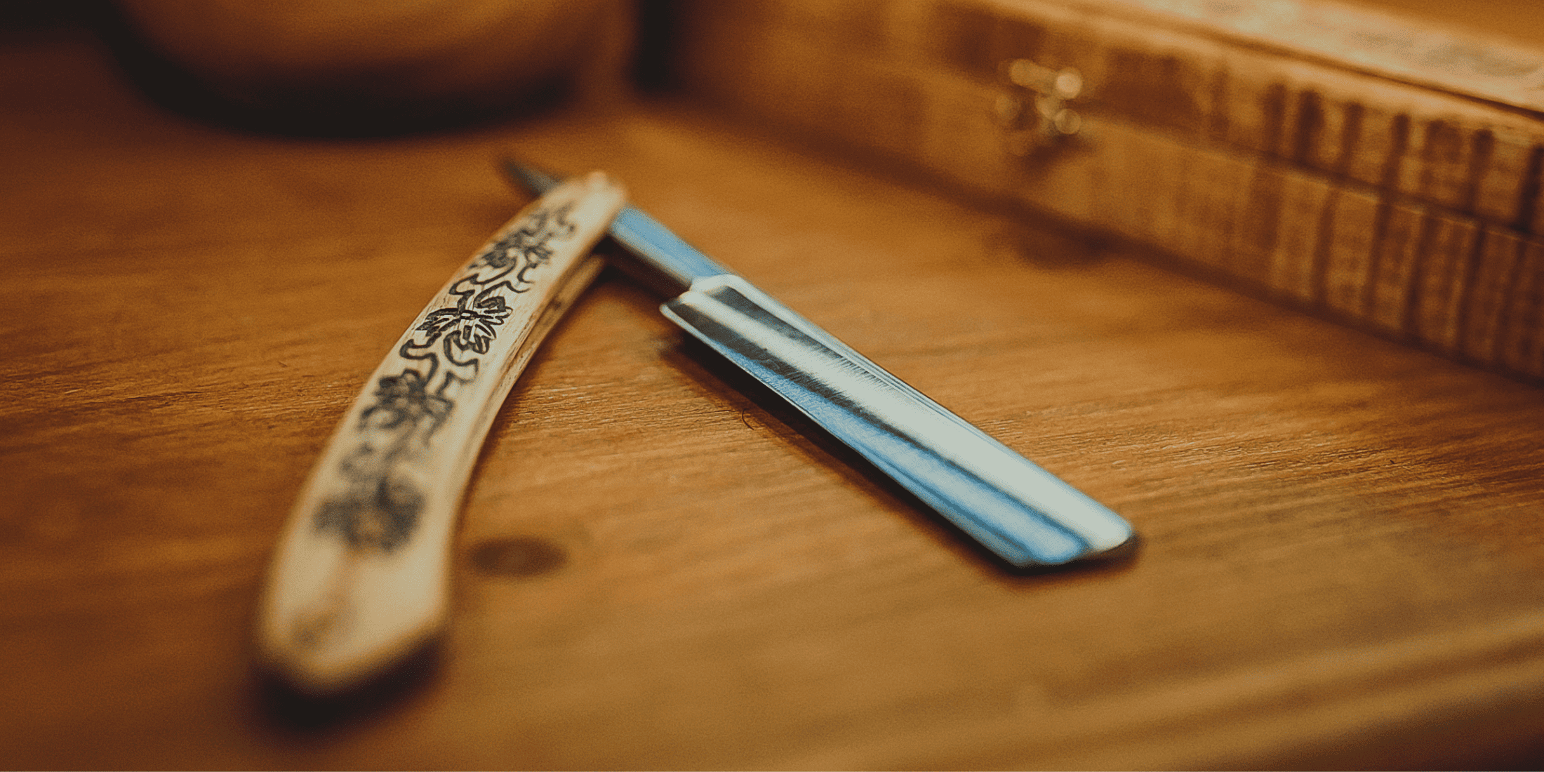 Close-up of a vintage straight razor with an intricately designed handle, resting on a wooden surface. This image highlights the elegance and tradition of straight razors, making it ideal for discussing how often you should change or sharpen your razor blades for optimal shaving performance and longevity.