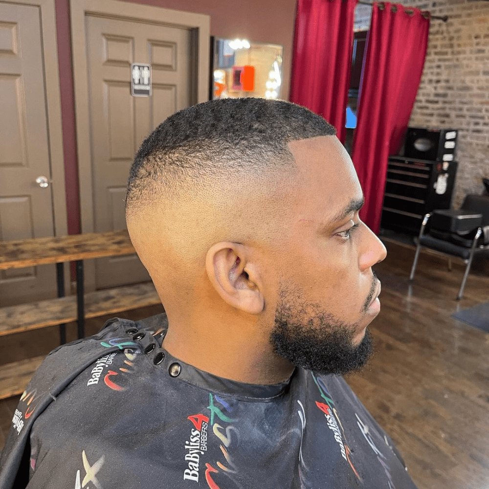 Man with a bald high fade short fade haircut. The hairstyle features a clean, close-cut high fade on the sides and back, blending into a short length on top. This bold and modern look is perfect for men's hairstyles in 2024, offering a sharp and polished appearance.