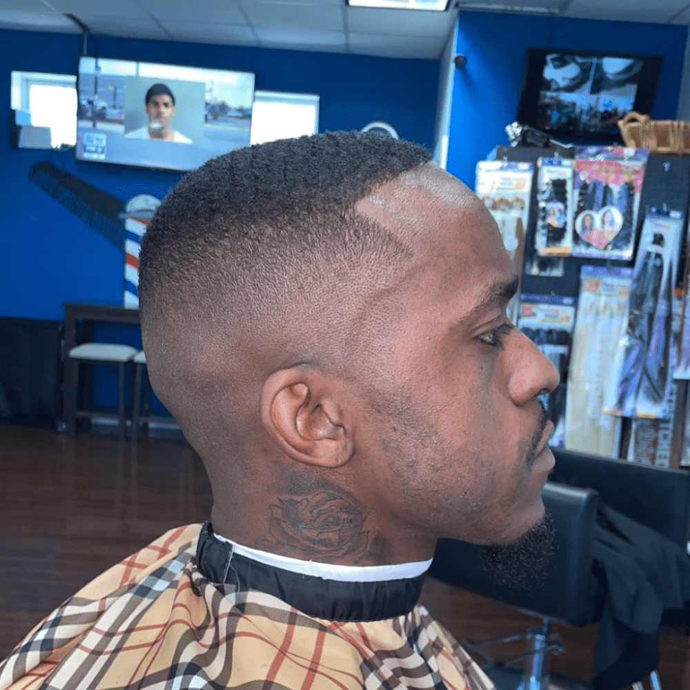 Side profile of a man with a Boosie haircut, featuring very short, even hair on top with a high skin fade on the sides and back. The hairstyle highlights a sharp and distinctive look, popularized by rapper Boosie Badazz, making it an ideal choice for men seeking bold haircuts