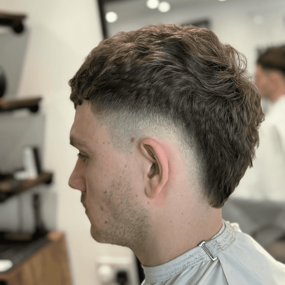 Side profile of a stylish burst fade haircut featuring a bold, circular fade pattern around the ear. Perfect for adding volume and texture to straight or wavy hair. Explore the differences between burst fade vs drop fade in our comprehensive guide.