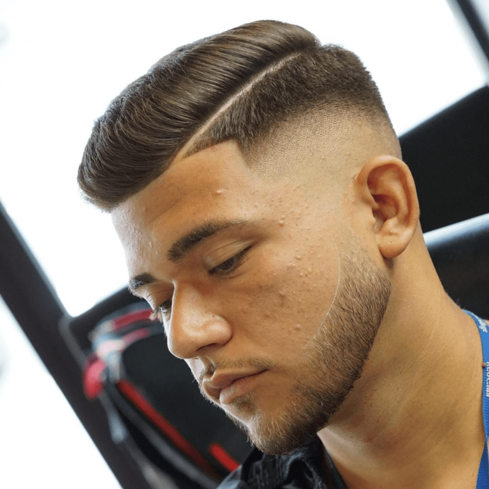 Side profile of a man with a Comb-Over Fade haircut, featuring neatly combed hair to the side with a hard part and a clean fade on the sides and back. The hairstyle highlights a polished and sophisticated look, making it a popular choice for men seeking trendy fade haircuts