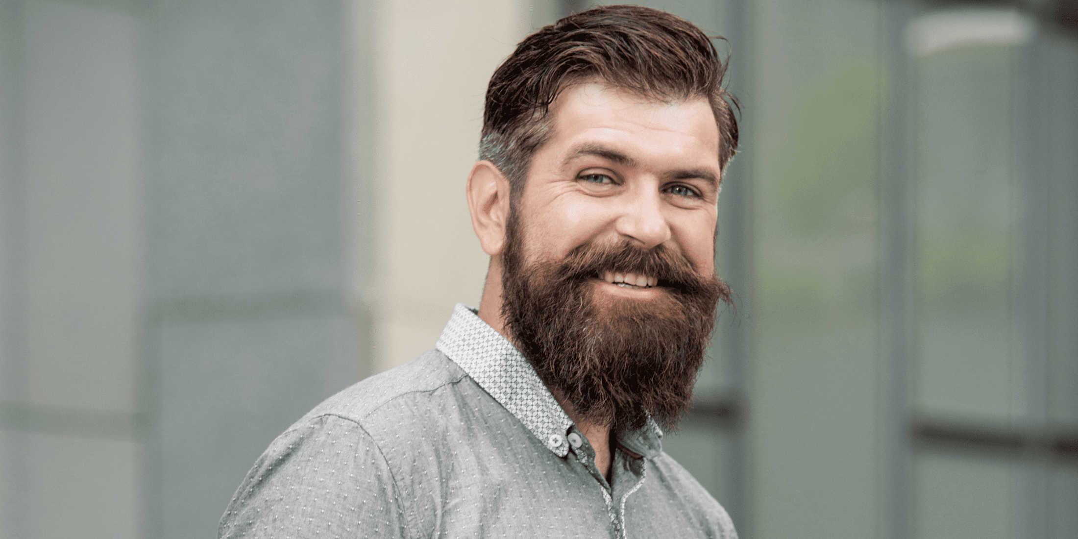 Smiling man with a thick, well-groomed beard, debunking the common myth about beard growth that beards make you look older. Highlighting how proper beard care and grooming can enhance facial features and style.