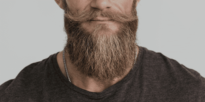 A close-up image of a well-groomed man with a full, textured beard and styled mustache. Perfect for an article on how to make your beard soft. 