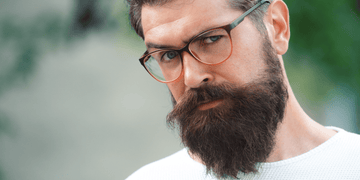 Close-up of a man with glasses and a well-maintained beard, showcasing a healthy, dandruff-free beard. Learn how to get rid of beard dandruff with effective tips and natural remedies.