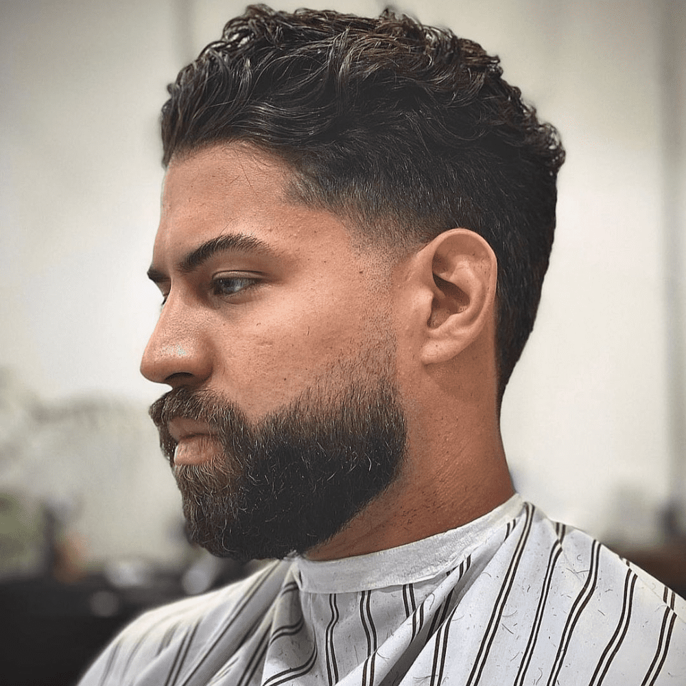 Side profile of a man with a Scissor Fade haircut, featuring medium-length, textured hair on top and a clean, blended fade on the sides and back achieved using scissors. The hairstyle provides a natural and sophisticated look, perfect for men seeking trendy and classic fade haircuts.