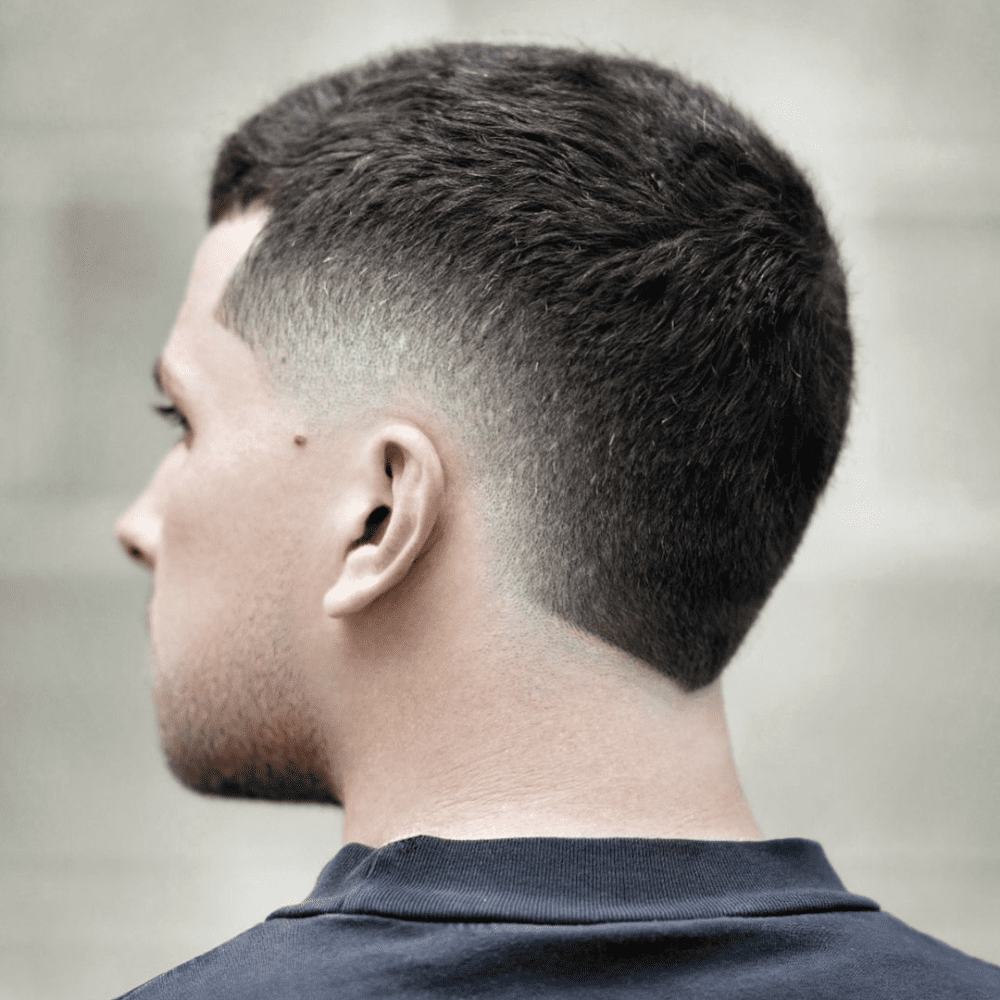 Side profile of a man with a Short Hair Burst Fade haircut, highlighting a neat and low-maintenance style. The hair on top is kept short and evenly trimmed, while the burst fade smoothly tapers down from the temples to the nape of the neck. This fade creates a clean and sharp look, ideal for those who prefer a straightforward yet stylish appearance. The background is blurred, keeping the focus on the well-executed haircut. This style is perfect for active individuals seeking an easy-to-manage and modern look.