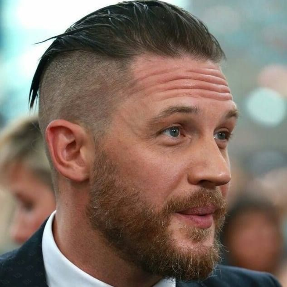 Close-up of a man with a slicked back undercut hairstyle, featuring short sides and a longer top, paired with a well-groomed beard. This stylish and edgy look is perfect for men seeking a modern variation of the slicked back haircut in 2024, showcasing a bold contrast and a sleek finish.