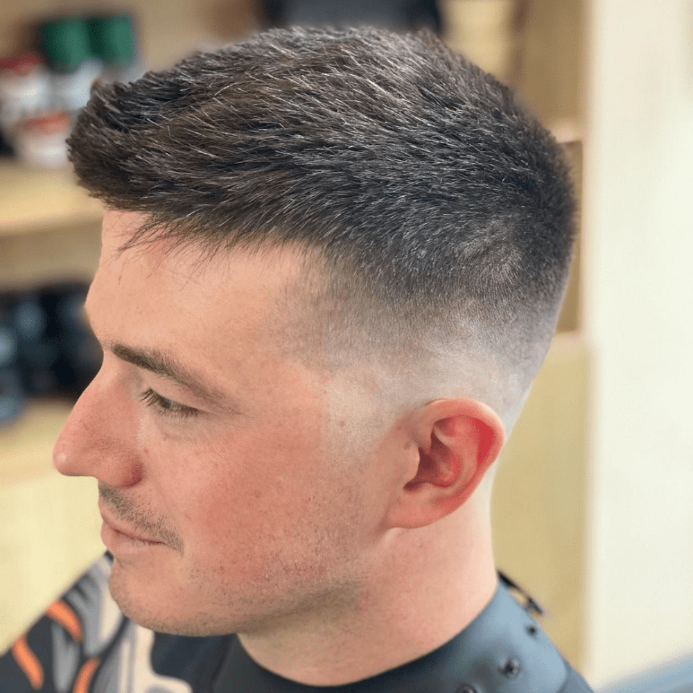 Side profile of a man with a Spiky Top Skin Fade haircut, featuring short, spiky hair on top with a clean skin fade on the sides and back. The hairstyle offers a modern and edgy look, making it a trendy choice for men seeking stylish fade haircuts